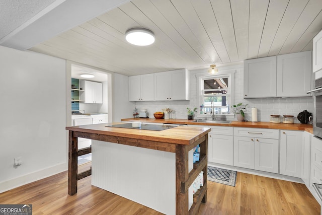 132 4th St, Meldrim, GA 31318 - kitchen featuring light wood finished floors, a sink, wood counters, black electric stovetop, and washing machine and dryer