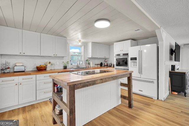 132 4th St, Meldrim, GA 31318 - kitchen with stainless steel oven, black electric cooktop, white fridge with ice dispenser, and wooden counters