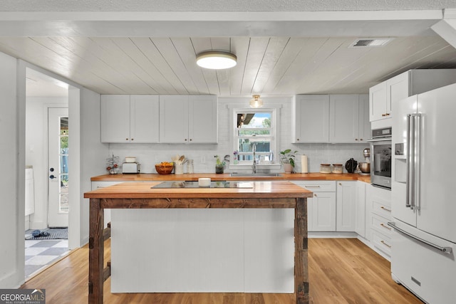 132 4th St, Meldrim, GA 31318 - kitchen featuring black electric stovetop, butcher block countertops, stainless steel oven, high end white refrigerator, and light wood-style floors