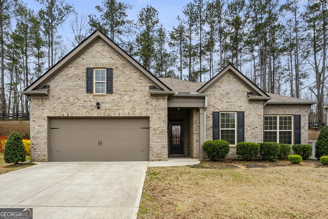 view of front of home featuring driveway, roof with shingles, a front lawn, a garage, and brick siding