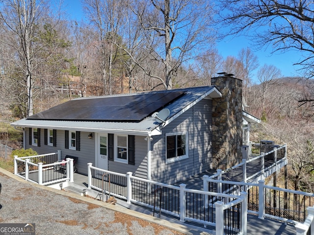 625 Sunnyside Shores Rd, Hiawassee, GA 30546 - view of front facade featuring roof mounted solar panels, covered porch, and a chimney
