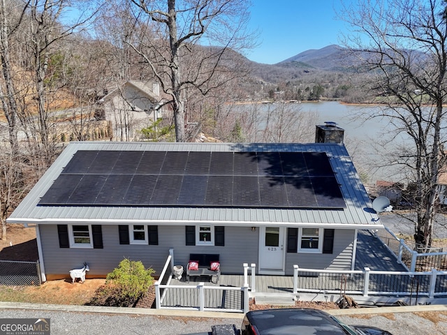 625 Sunnyside Shores Rd, Hiawassee, GA 30546 - view of front of home featuring roof mounted solar panels, covered porch, a water and mountain view, and a chimney