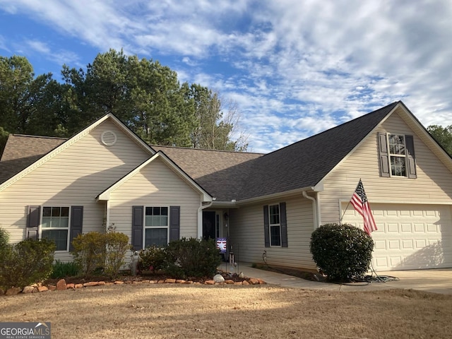 view of front of property with roof with shingles, an attached garage, and driveway