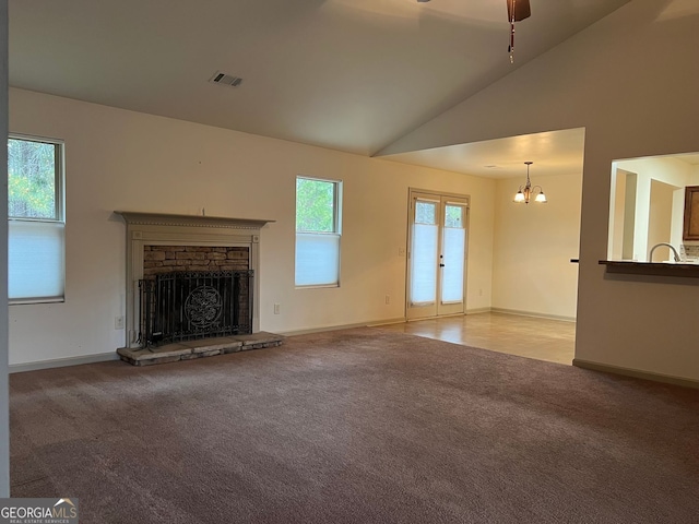 unfurnished living room with a stone fireplace, visible vents, baseboards, lofted ceiling, and carpet flooring