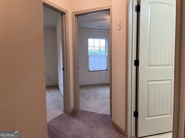 hallway with baseboards and light carpet