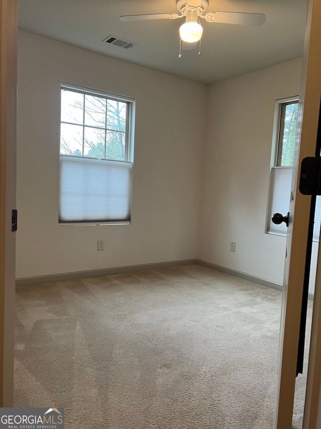unfurnished room with carpet flooring, ceiling fan, visible vents, and baseboards