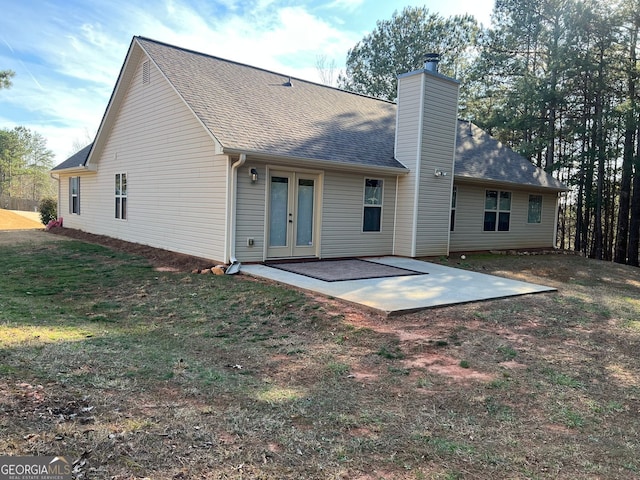 back of property with a patio, french doors, a shingled roof, and a chimney