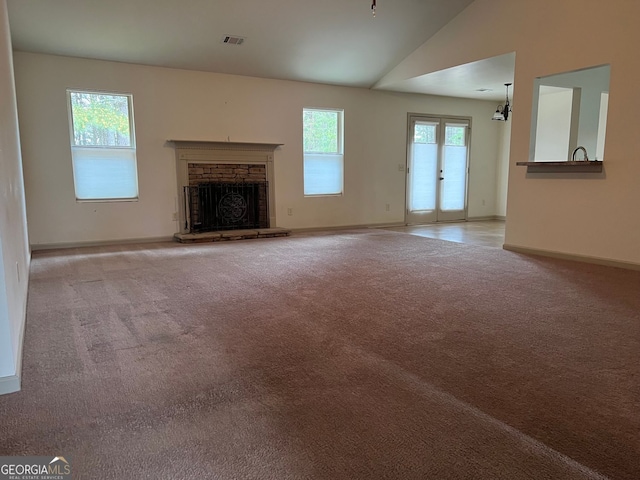 unfurnished living room with carpet flooring, a fireplace, baseboards, vaulted ceiling, and visible vents