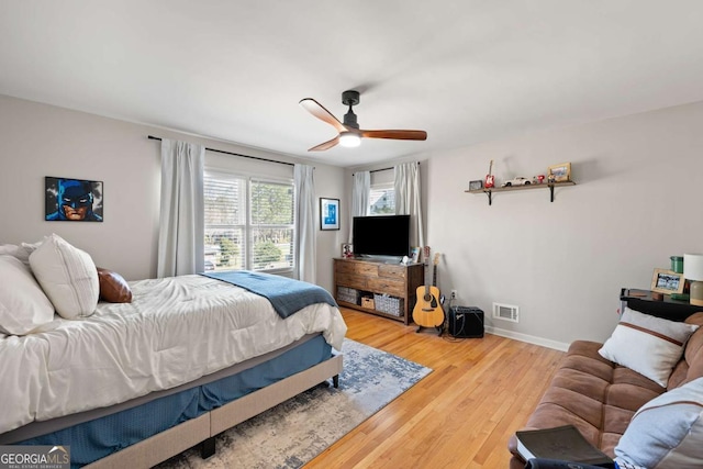 bedroom with visible vents, a ceiling fan, baseboards, and wood finished floors
