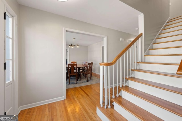 staircase with an inviting chandelier, baseboards, and wood-type flooring