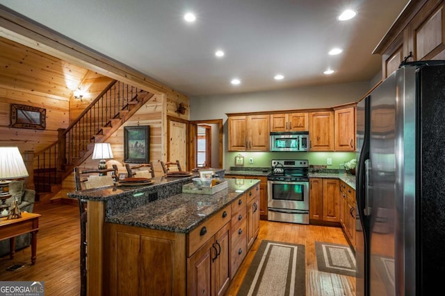 2778 Kelly Ln, Hiawassee, GA 30546 - kitchen with appliances with stainless steel finishes, brown cabinets, a kitchen bar, wooden walls, and light wood-type flooring