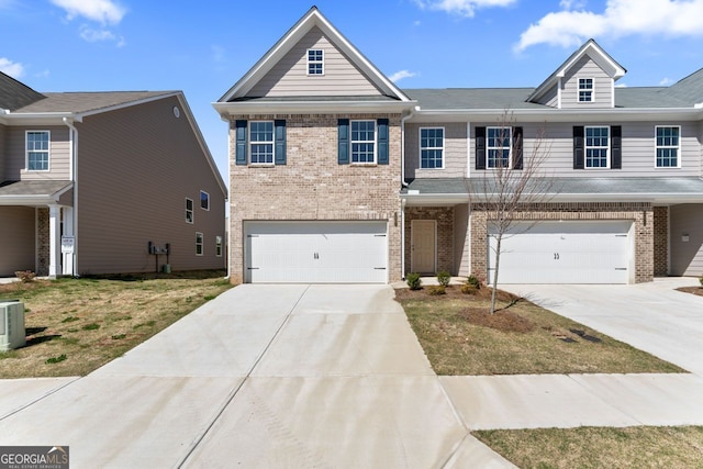 multi unit property with brick siding, driveway, and an attached garage