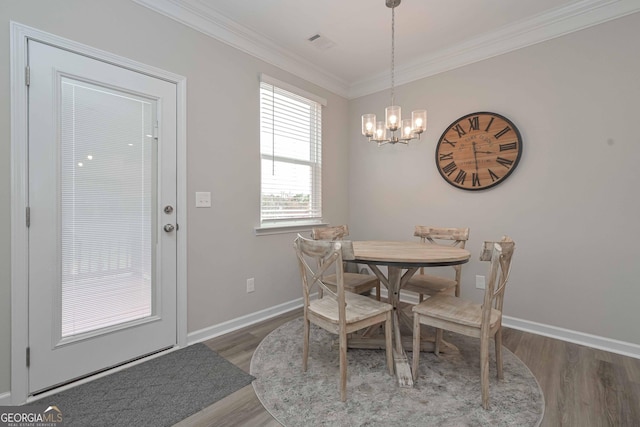 dining space with baseboards, crown molding, wood finished floors, and an inviting chandelier