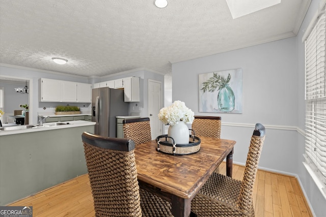 dining area with light wood-type flooring, a textured ceiling, and crown molding