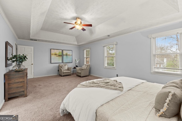 carpeted bedroom with a textured ceiling, baseboards, visible vents, ceiling fan, and a raised ceiling