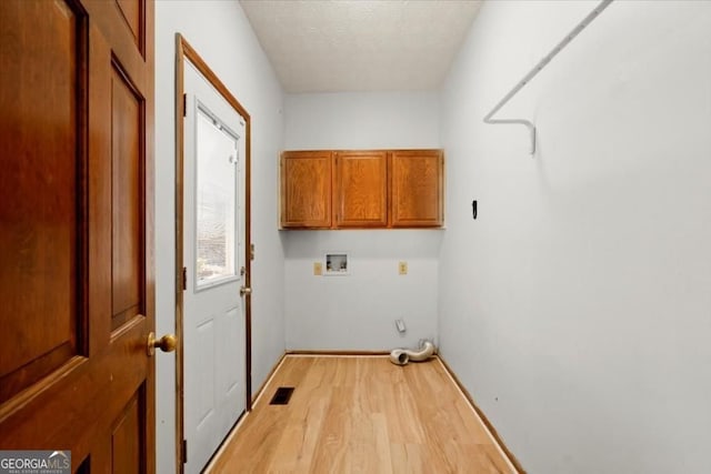 laundry room with a textured ceiling, baseboards, light wood-style floors, washer hookup, and cabinet space