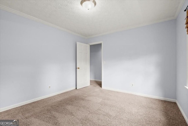 spare room with carpet floors, crown molding, a textured ceiling, and baseboards