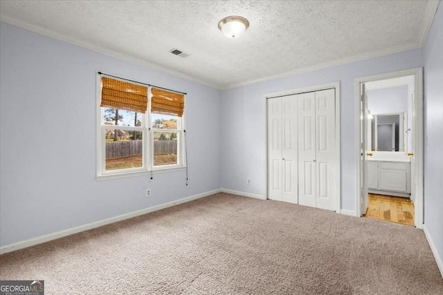 unfurnished bedroom featuring a textured ceiling, carpet, visible vents, and ornamental molding