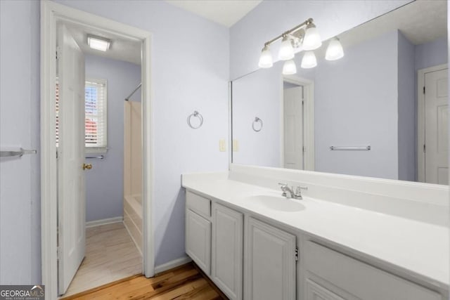 full bath with baseboards, wood finished floors, shower / bath combo with shower curtain, and vanity