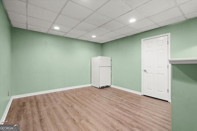 spare room with baseboards, wood finished floors, a drop ceiling, and recessed lighting