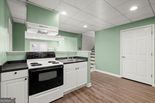 kitchen featuring white cabinets, a sink, light wood-type flooring, dark countertops, and electric stove