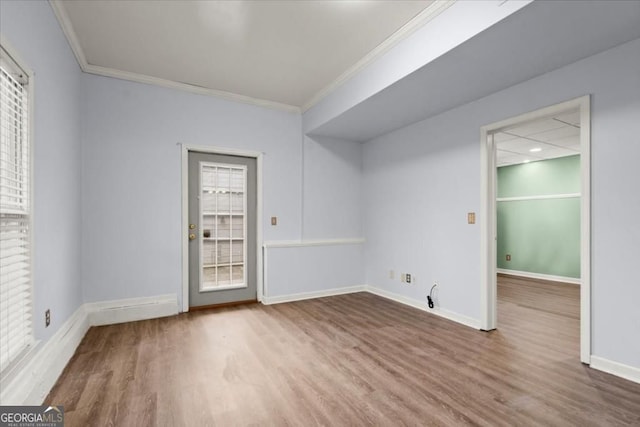 empty room with baseboards, wood finished floors, and crown molding