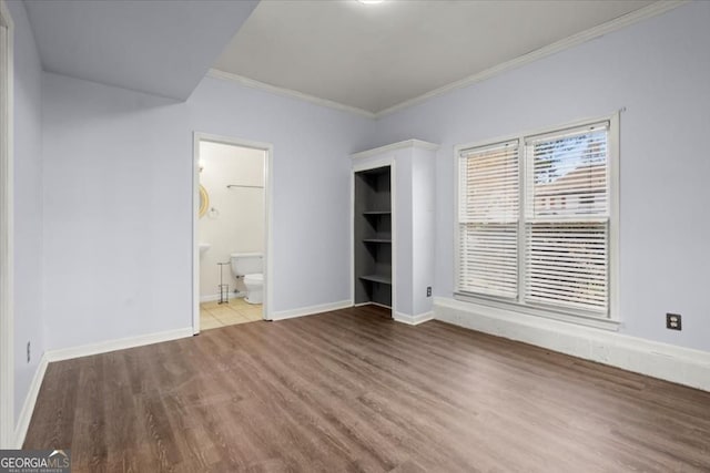interior space featuring ensuite bath, baseboards, crown molding, and wood finished floors