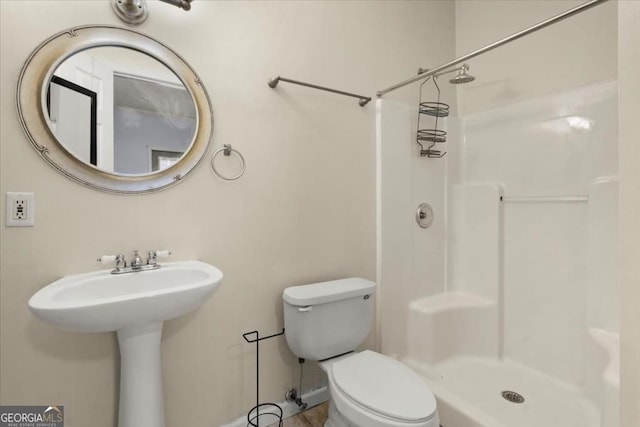 full bath featuring baseboards, a sink, a shower stall, and toilet