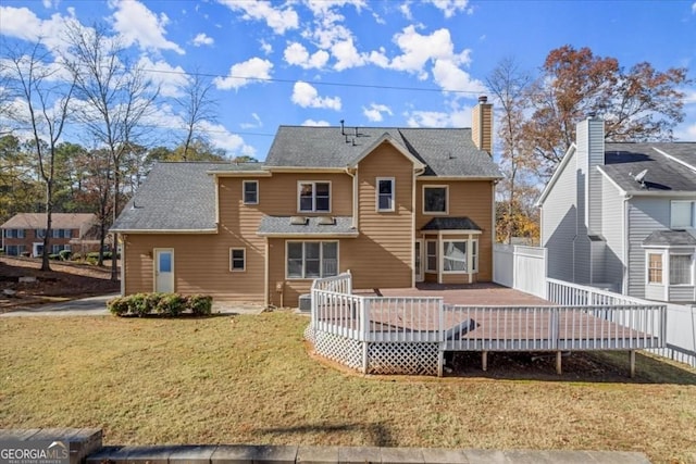 rear view of house with a yard, fence, and a deck