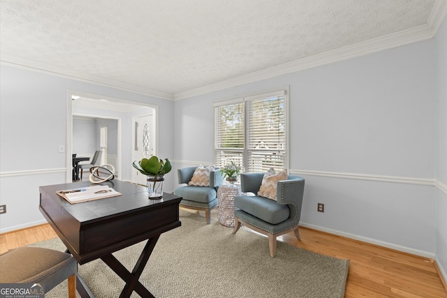 office with light wood finished floors, baseboards, a textured ceiling, and ornamental molding