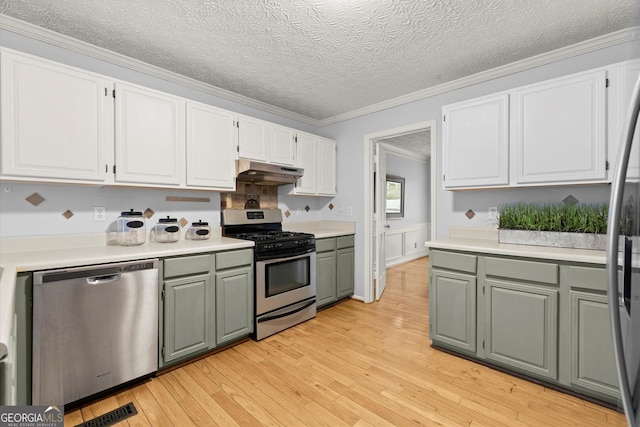 kitchen with stainless steel appliances, light countertops, under cabinet range hood, and white cabinetry