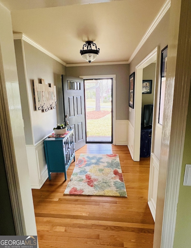 entryway featuring a decorative wall, a wainscoted wall, wood finished floors, and ornamental molding