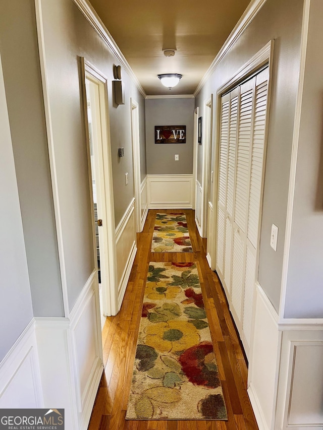 hallway with dark wood-style flooring, ornamental molding, and a decorative wall