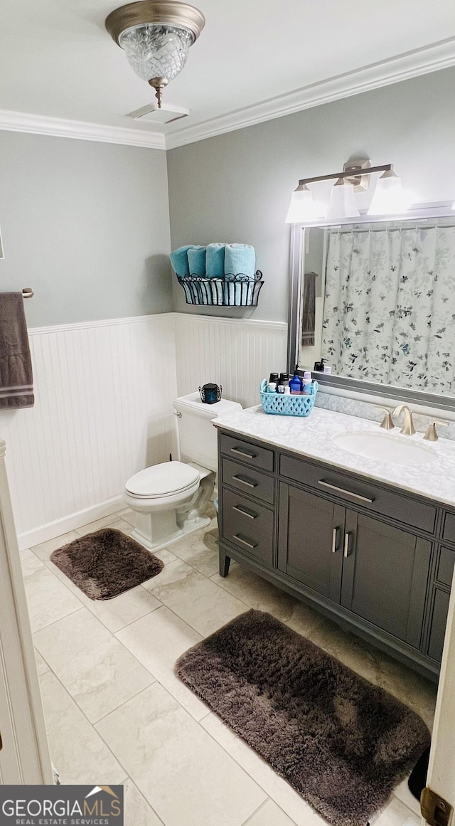 full bathroom with toilet, a wainscoted wall, a shower with shower curtain, vanity, and ornamental molding
