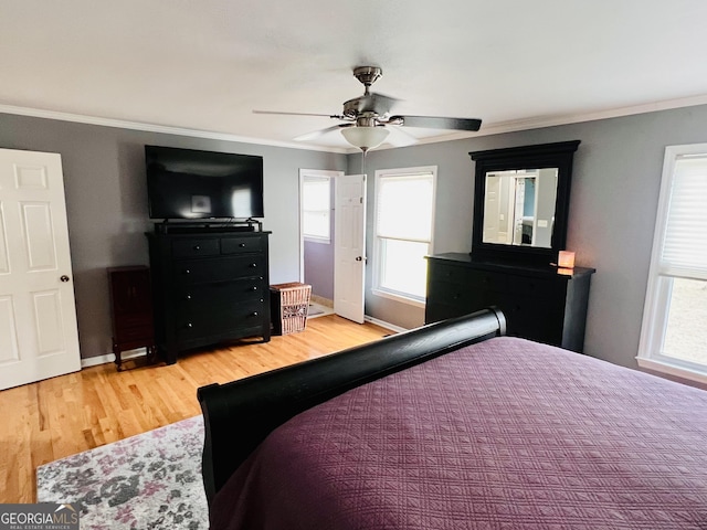 bedroom featuring crown molding, baseboards, light wood-type flooring, and a ceiling fan