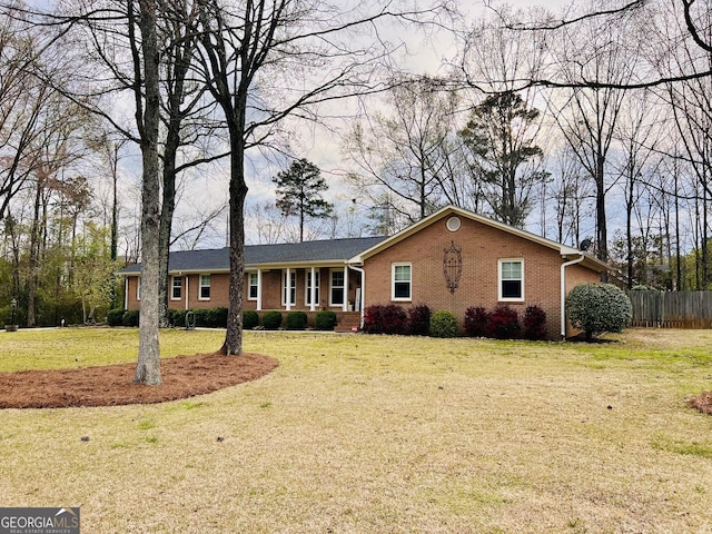 ranch-style home featuring a front lawn, brick siding, and fence
