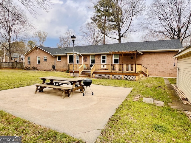 back of property featuring a yard, brick siding, fence, a patio area, and a deck