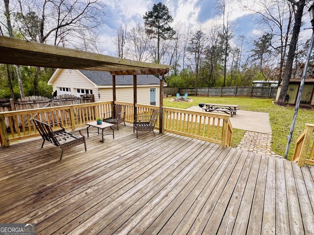 wooden terrace featuring a fenced backyard, an outdoor structure, a fire pit, and a yard