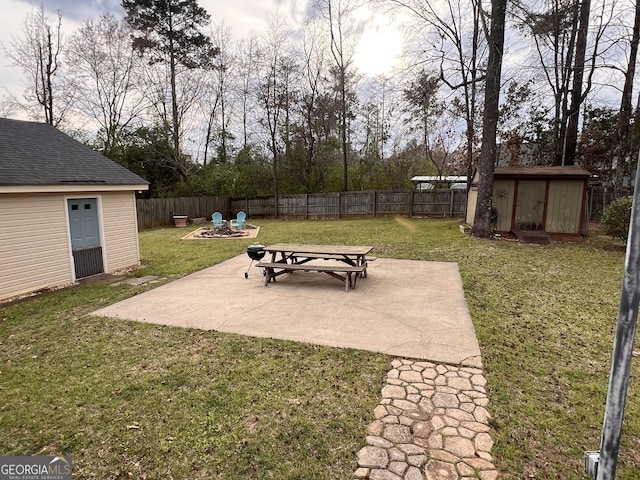 view of patio featuring a fenced backyard, an outdoor fire pit, a shed, and an outbuilding