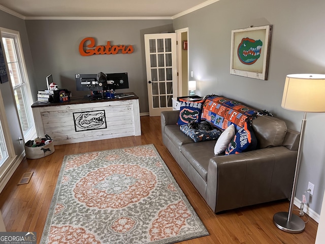 living room with visible vents, wood finished floors, baseboards, and ornamental molding