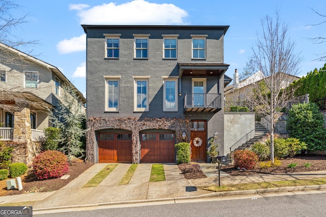 view of property featuring a garage, concrete driveway, a balcony, brick siding, and stairway