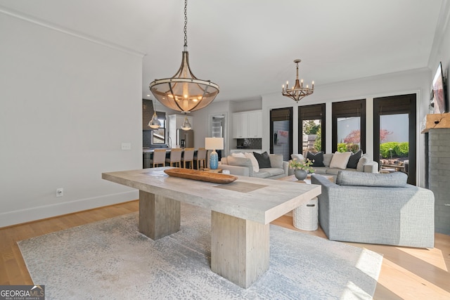 dining space with a chandelier, baseboards, and light wood-style flooring