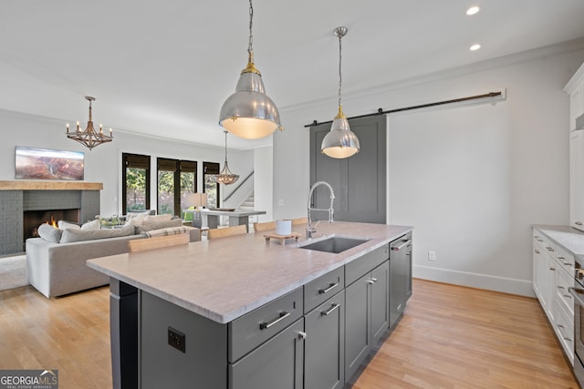 kitchen with a sink, a kitchen island with sink, gray cabinetry, recessed lighting, and a barn door