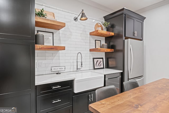 kitchen with open shelves, a sink, backsplash, freestanding refrigerator, and ornamental molding