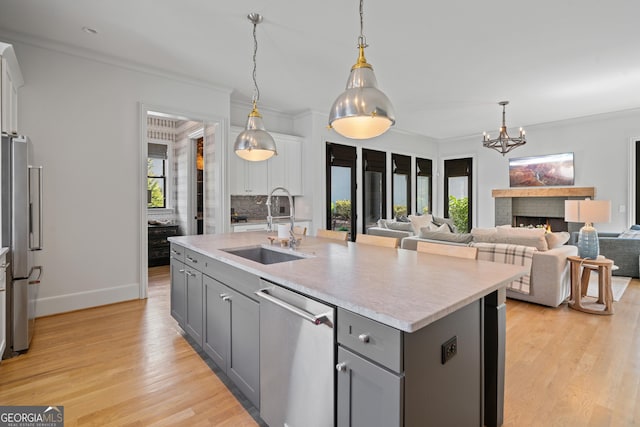 kitchen featuring gray cabinetry, a sink, appliances with stainless steel finishes, light countertops, and light wood-style floors