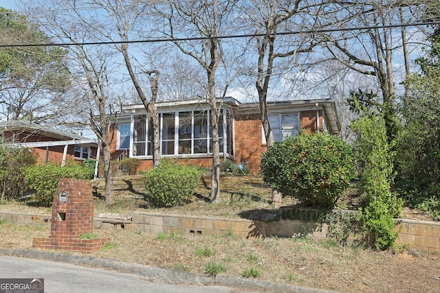 view of front of property with brick siding and a sunroom