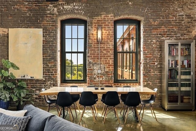 dining space with brick wall and a healthy amount of sunlight