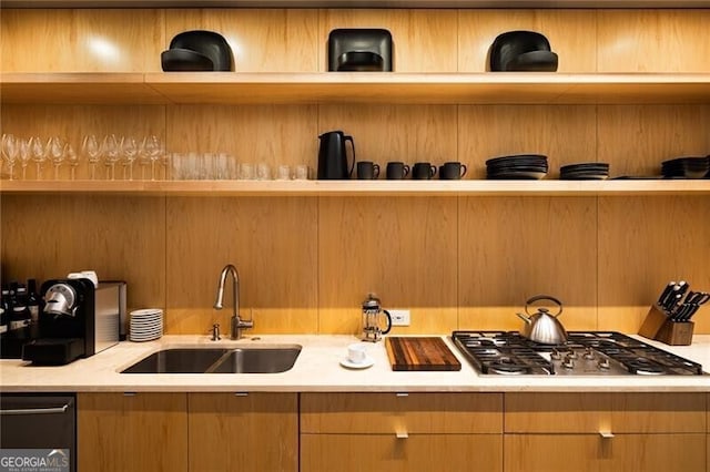 kitchen featuring light countertops, a sink, open shelves, and stainless steel gas stovetop
