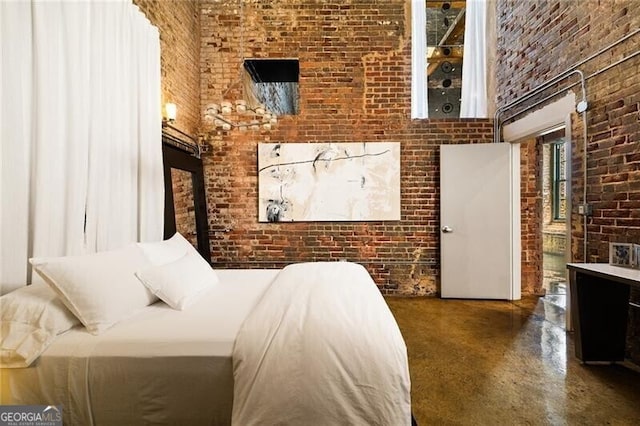 bedroom featuring brick wall, a towering ceiling, and finished concrete flooring