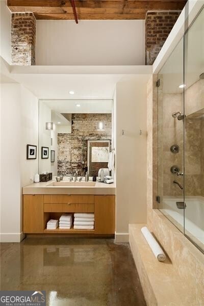 bathroom with shower / bath combination with glass door, vanity, baseboards, and finished concrete flooring